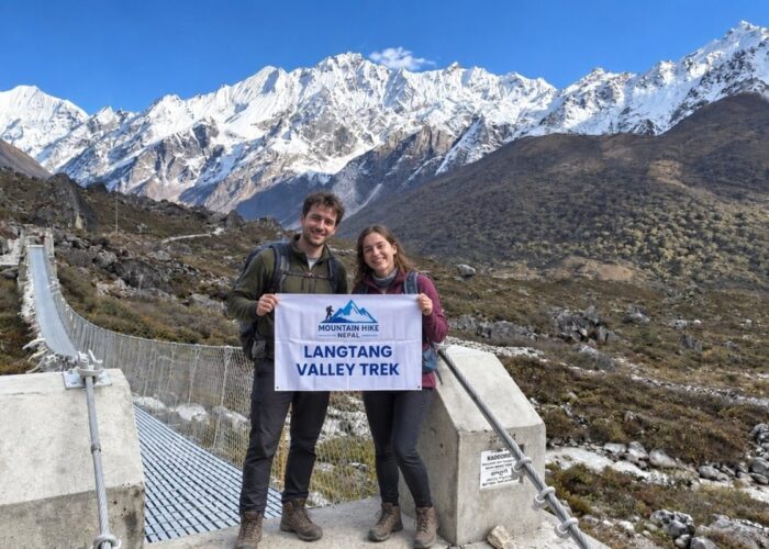 Trekkers on the Langtang Valley trail with snow-covered Himalayan mountains