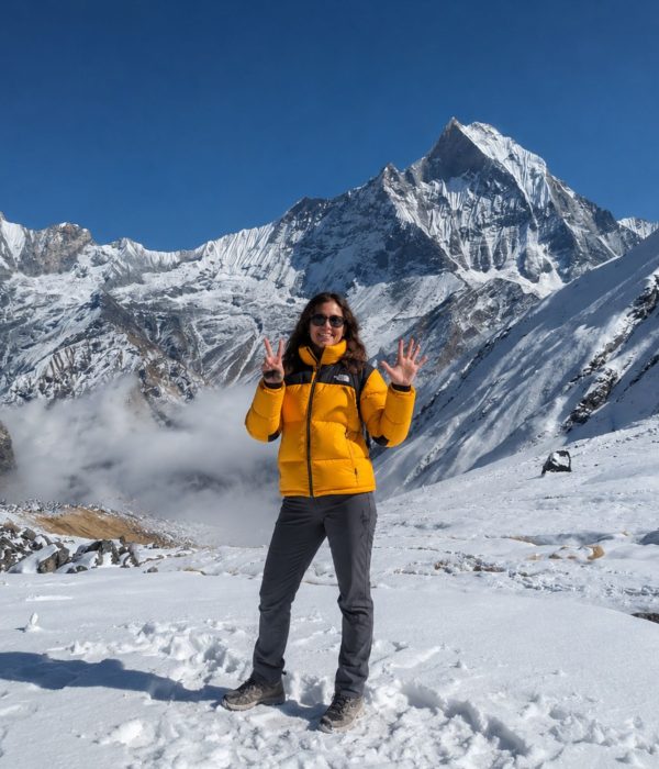 Trekker at Annapurna Base Camp with Machapuchare (Fishtail) peak and Annapurna III in the background