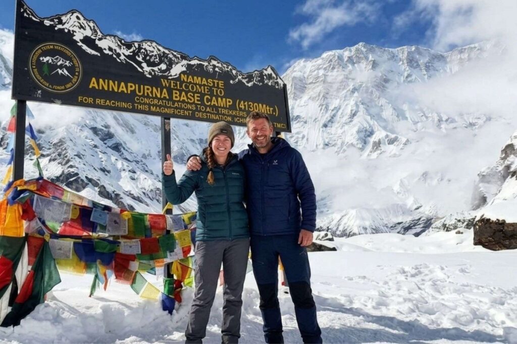 Trekkers at Annapurna Base Camp surrounded by snow-covered Himalayan mountains