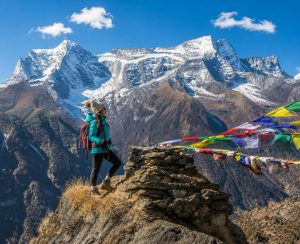 EBC Trek Viewpoint with Stunning Ama Dablam Scenery Female trekker standing at a mountain viewpoint during the EBC Trek with Ama Dablam and colorful prayer flags in the background.
