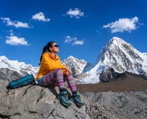 Relaxing Along the Everest Base Camp Trail in Nepal Female trekker resting on a rock along the Everest Base Camp Trail with snow-covered Himalayan mountains in the background.