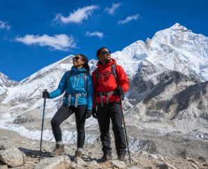 Everest Base Camp Trek in Nepal with Himalayan Mountain Views Trekking couple standing on a rocky trail during the Everest Base Camp Trek in Nepal with snow-covered Himalayan peaks behind them.