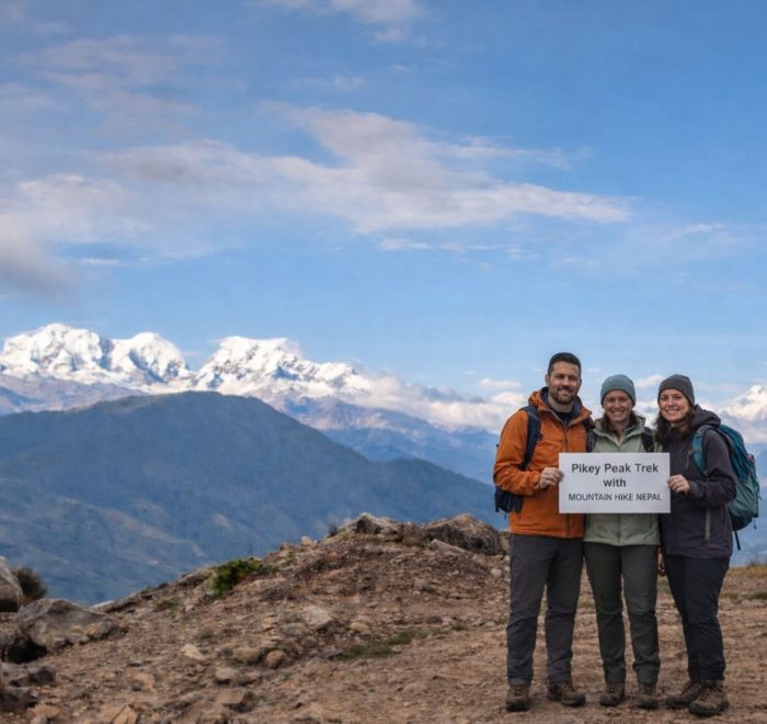 Trekkers standing at Pikey Peak summit with wide Himalayan mountain views