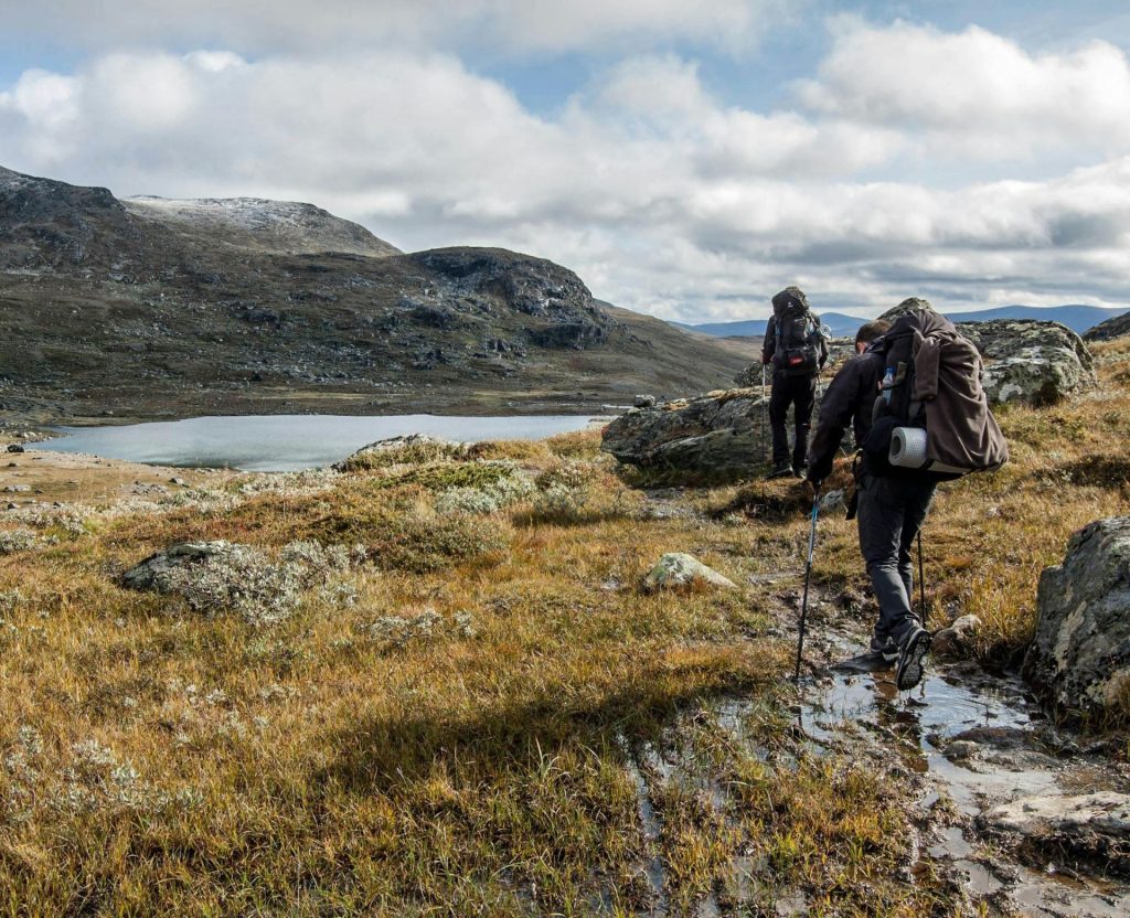 Trekkers walking beside a high mountain lake on the Langtang Helambu Circuit Trek