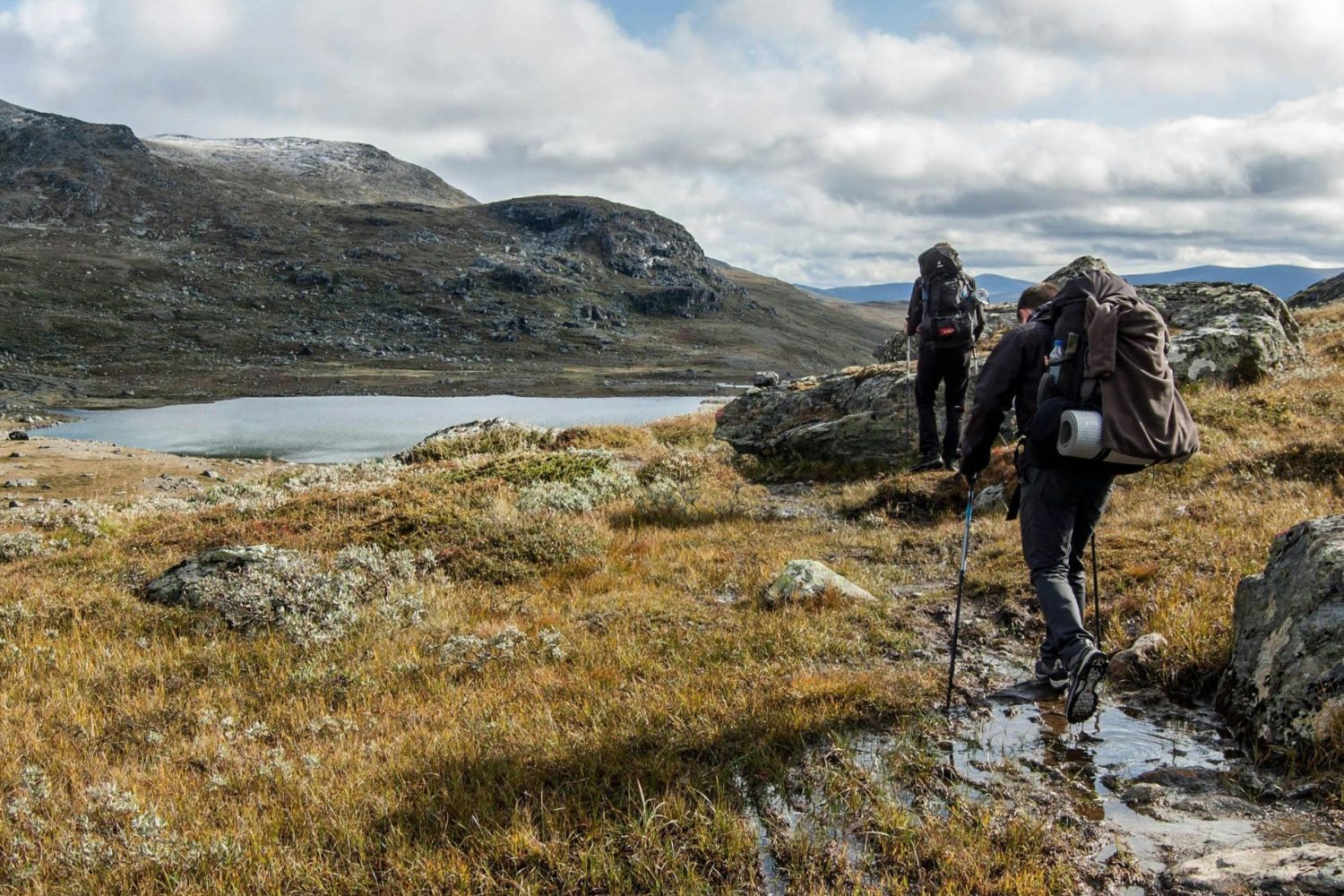 Trekkers walking beside a high mountain lake on the Langtang Helambu Circuit Trek