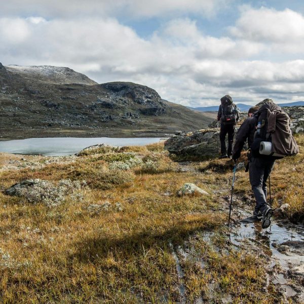Trekkers walking beside a high mountain lake on the Langtang Helambu Circuit Trek