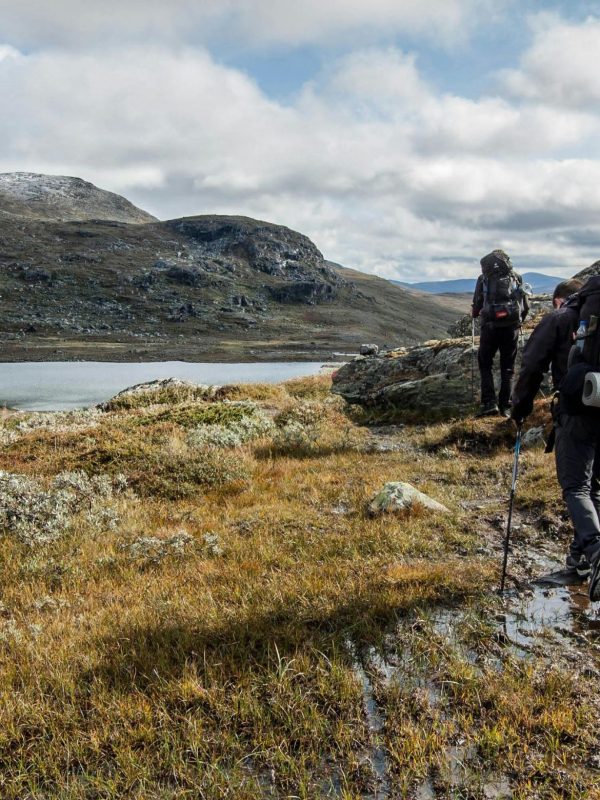 Trekkers walking beside a high mountain lake on the Langtang Helambu Circuit Trek