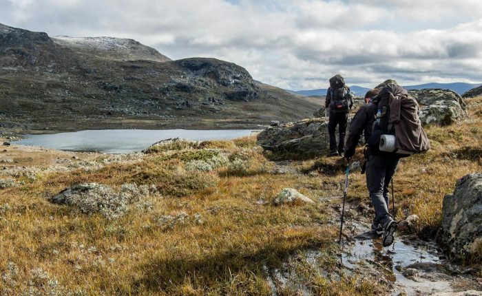 Trekkers walking beside a high mountain lake on the Langtang Helambu Circuit Trek