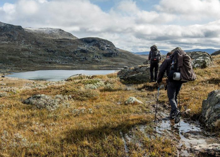 Trekkers walking beside a high mountain lake on the Langtang Helambu Circuit Trek