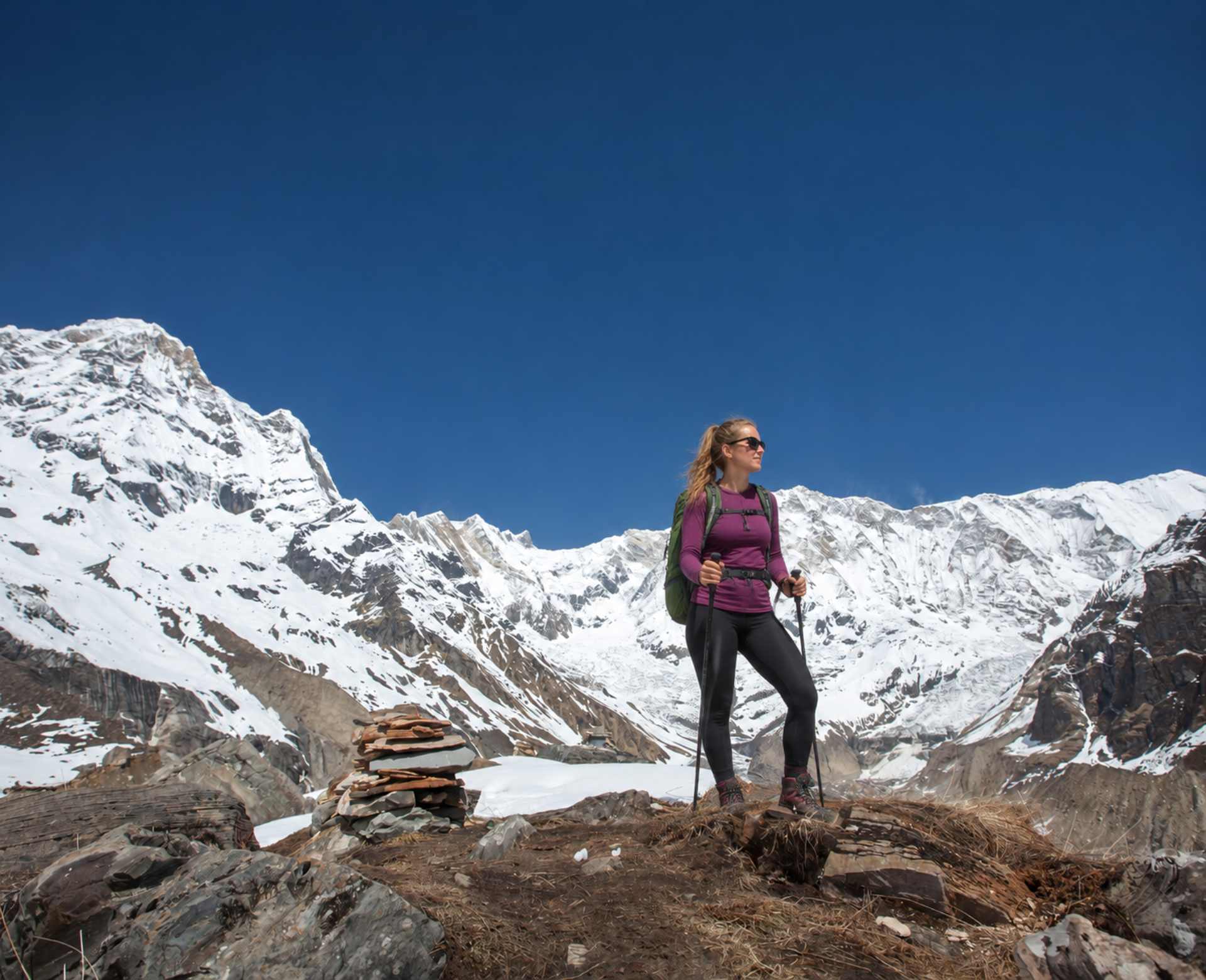 Annapurna Circuit trek for beginners with a female trekker standing on a mountain viewpoint overlooking the snow-covered Annapurna range in Nepal.