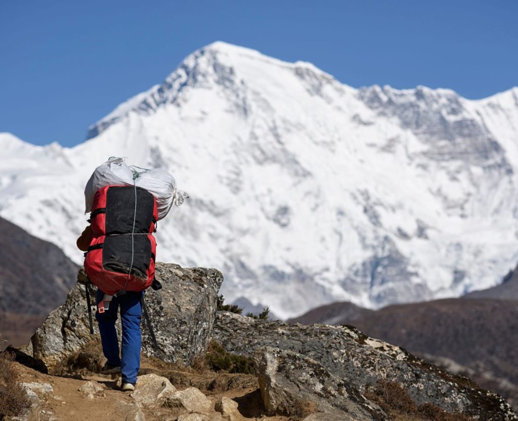 Nepal trekking porter carrying gear on high altitude Himalayan trail