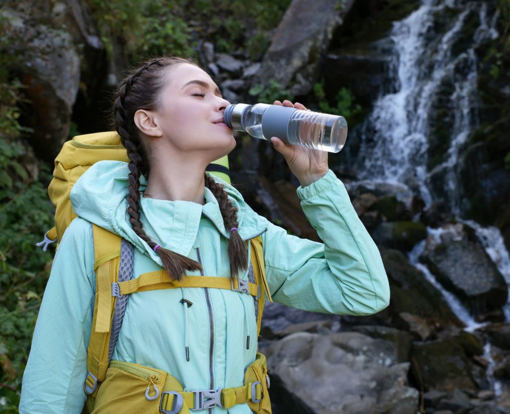 Female trekker drinking water during hike to prevent dehydration