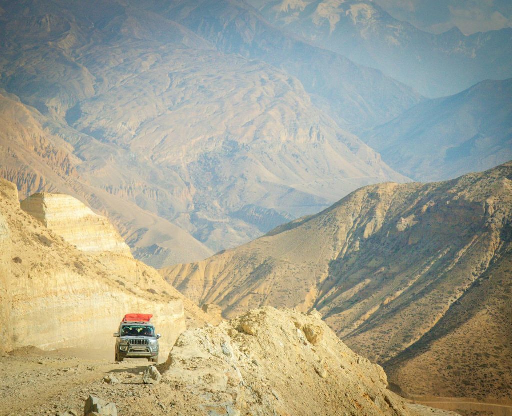 4WD jeep driving on rugged road in Upper Mustang Nepal landscape