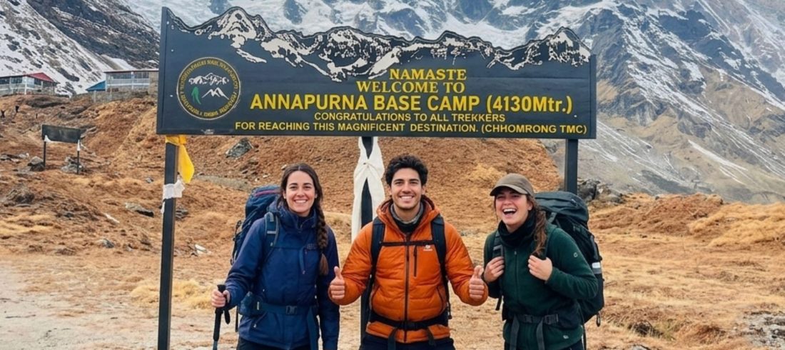 Trekkers posing at the Annapurna Base Camp sign with Annapurna mountains in the background during the Annapurna Base Camp Trek in Nepal.