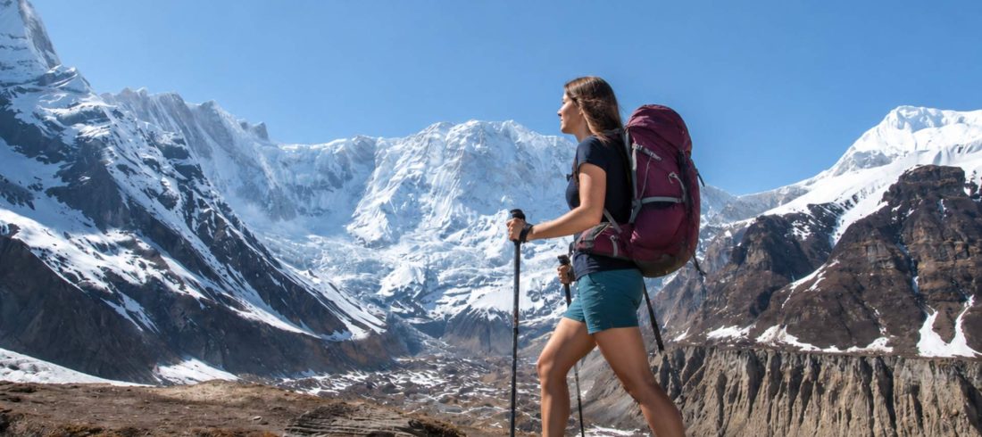 Solo trekker hiking on the Annapurna Base Camp trail with snow-capped Himalayan mountains in the background during an Annapurna Base Camp Trek Without Guide.