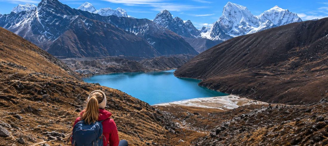Female trekker overlooking mountain lake and snowy peaks during the Cho La Pass trek in Nepal