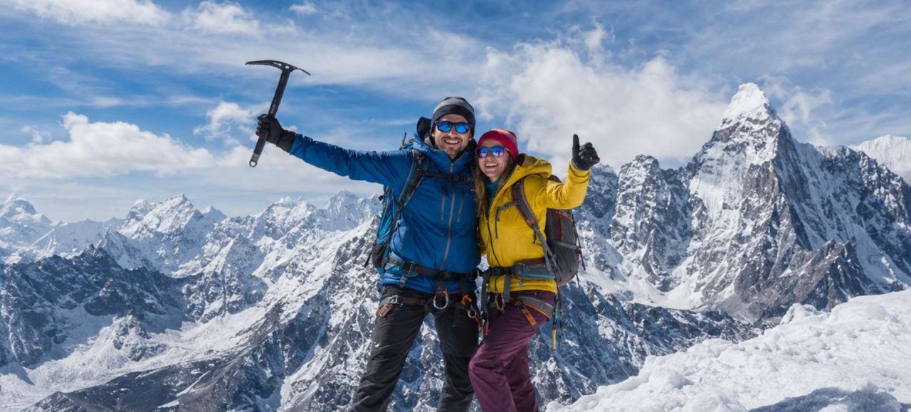 Mountaineering couple standing on a snowy Himalayan summit during Island Peak Climbing in Nepal with panoramic mountain views.
