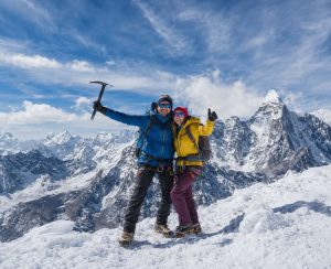Island Peak Climbing Summit Success with Himalayan Mountain Views Mountaineering couple standing on a snowy Himalayan summit during Island Peak Climbing in Nepal with panoramic mountain views.