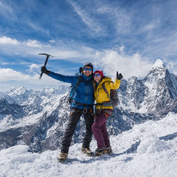 Mountaineering couple standing on a snowy Himalayan summit during Island Peak Climbing in Nepal with panoramic mountain views.