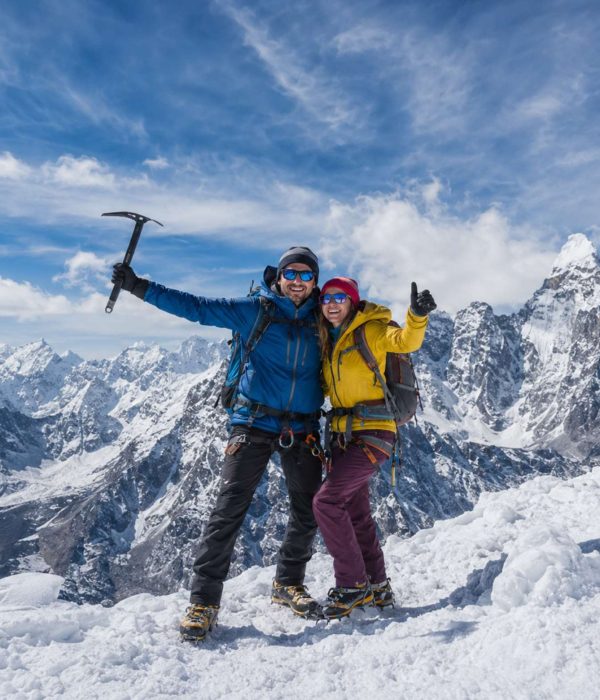 Mountaineering couple standing on a snowy Himalayan summit during Island Peak Climbing in Nepal with panoramic mountain views.