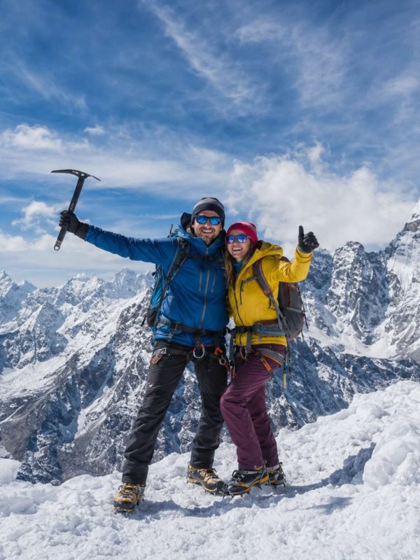 Mountaineering couple standing on a snowy Himalayan summit during Island Peak Climbing in Nepal with panoramic mountain views.
