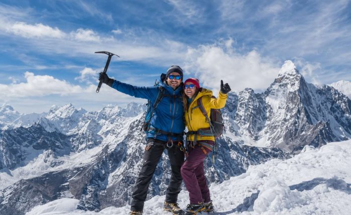Mountaineering couple standing on a snowy Himalayan summit during Island Peak Climbing in Nepal with panoramic mountain views.