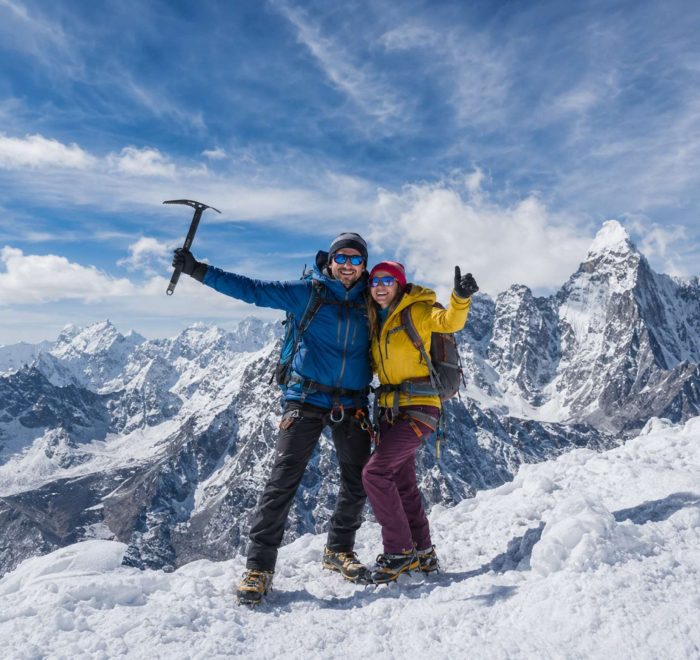 Mountaineering couple standing on a snowy Himalayan summit during Island Peak Climbing in Nepal with panoramic mountain views.