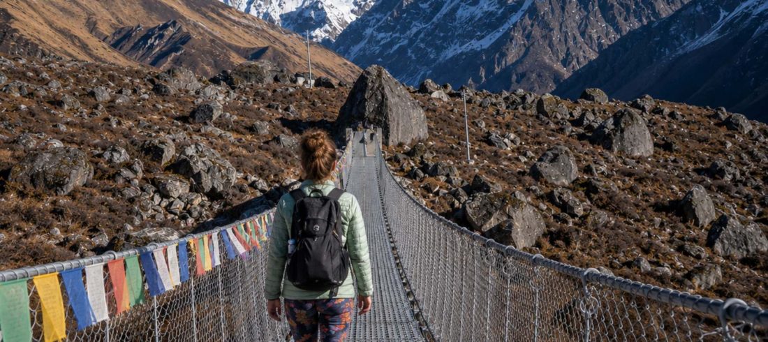 Beginner female trekker crossing a suspension bridge during the Langtang Valley Trek in Nepal