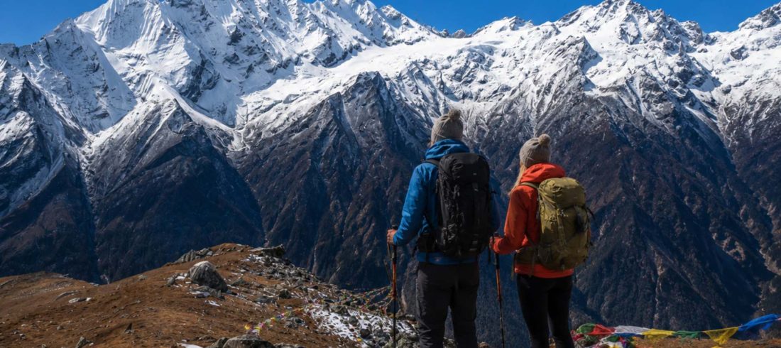 European trekking couple overlooking snowy Langtang Valley mountains during the Langtang Valley Trek itinerary in Nepal
