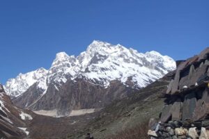 Mani Wall on the Trail from Samdo to Dharamsala, Manaslu Circuit Stone mani wall beside the trail from Samdo to Dharamsala, with snow-covered peaks and trekkers in the valley