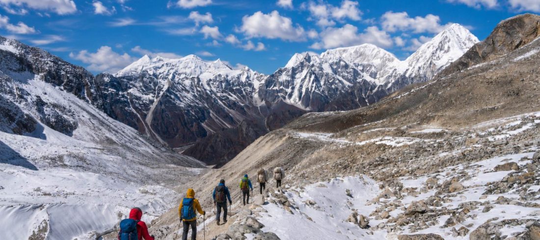Manaslu circuit trek cost trail in Nepal with trekkers crossing snowy Himalayan mountains under blue sky