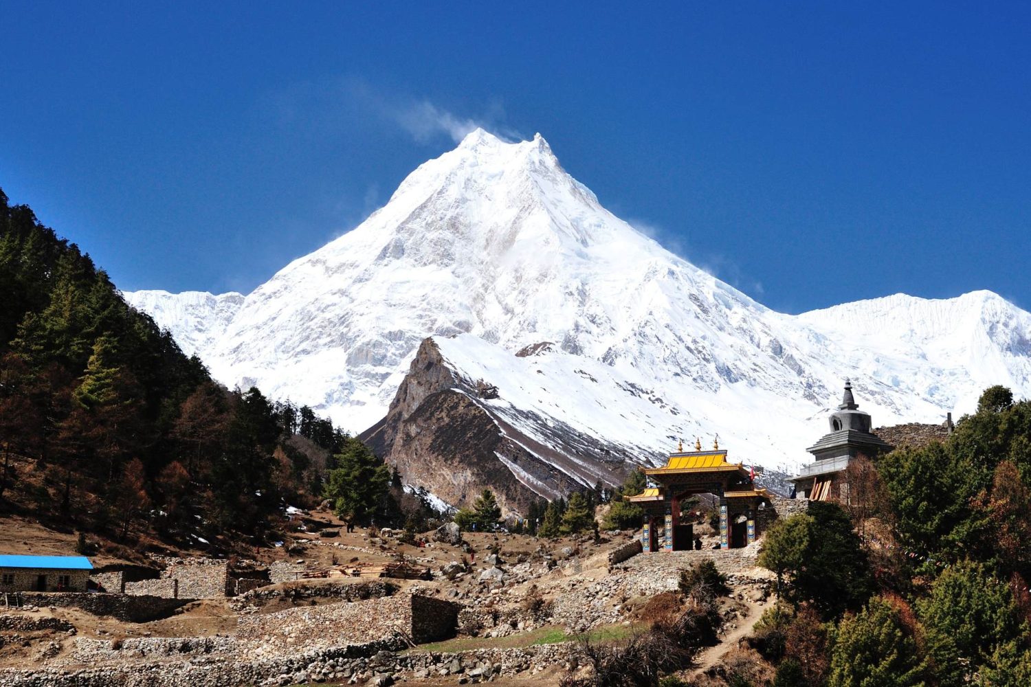 Manaslu Circuit Trek trail with Mount Manaslu and traditional gateway in Nepal