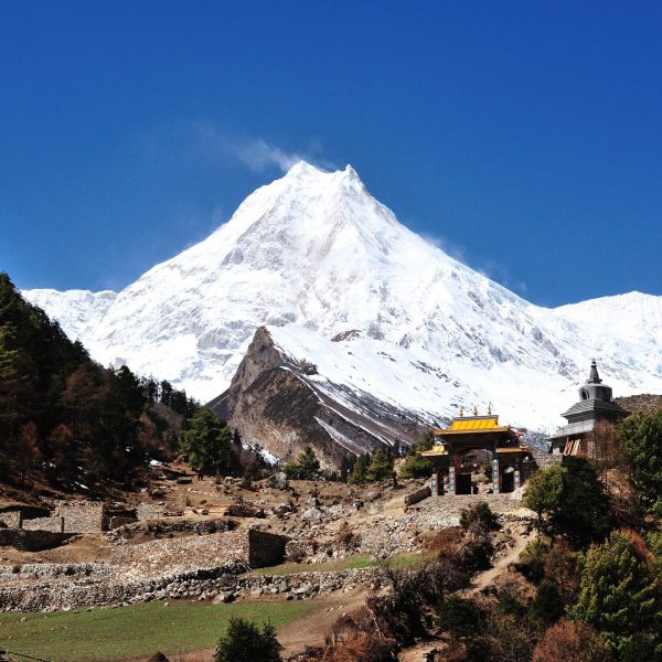 Manaslu Circuit Trek trail with Mount Manaslu and traditional gateway in Nepal