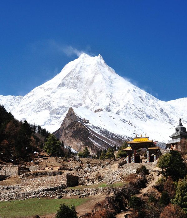 Manaslu Circuit Trek trail with Mount Manaslu and traditional gateway in Nepal