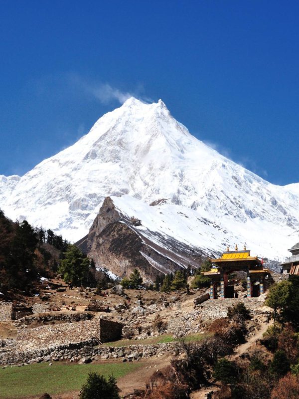 Manaslu Circuit Trek trail with Mount Manaslu and traditional gateway in Nepal