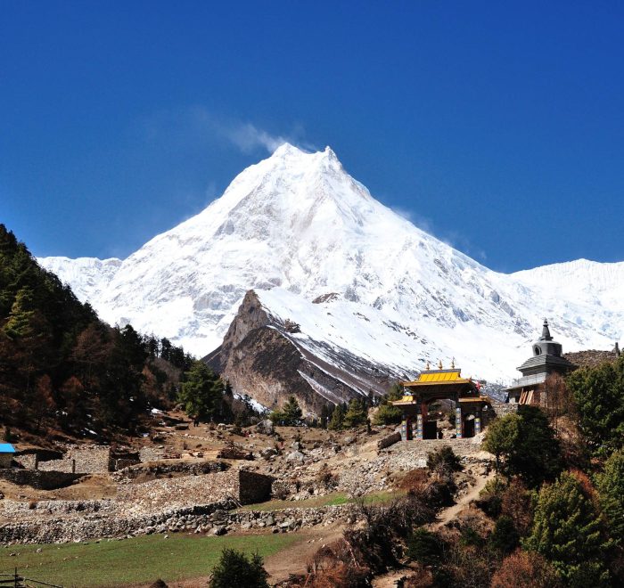 Manaslu Circuit Trek trail with Mount Manaslu and traditional gateway in Nepal