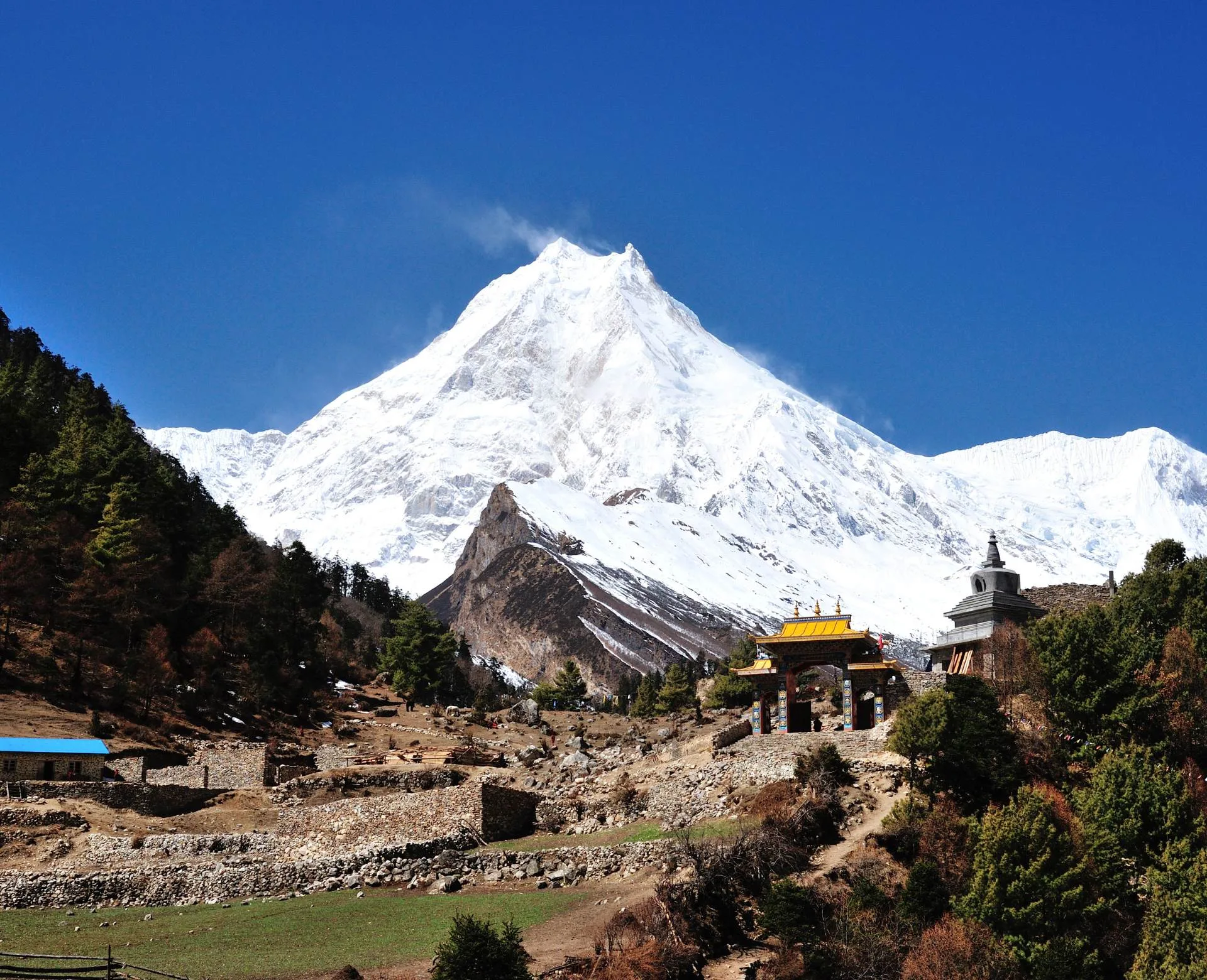 Manaslu Circuit Trek trail with Mount Manaslu and traditional gateway in Nepal