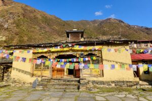 Mu Gompa in Upper Tsum Valley, Manaslu Tsum Valley Trek Front of Mu Gompa, a mud-plastered Buddhist monastery hung with prayer flags, above a stone-paved courtyard