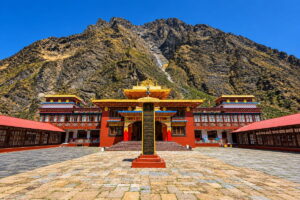 Rachen Gompa Nunnery Courtyard, Manaslu Tsum Valley Trek Courtyard of Rachen Gompa nunnery, with red and gold monastery buildings around a stone-paved square below a steep rocky mountain