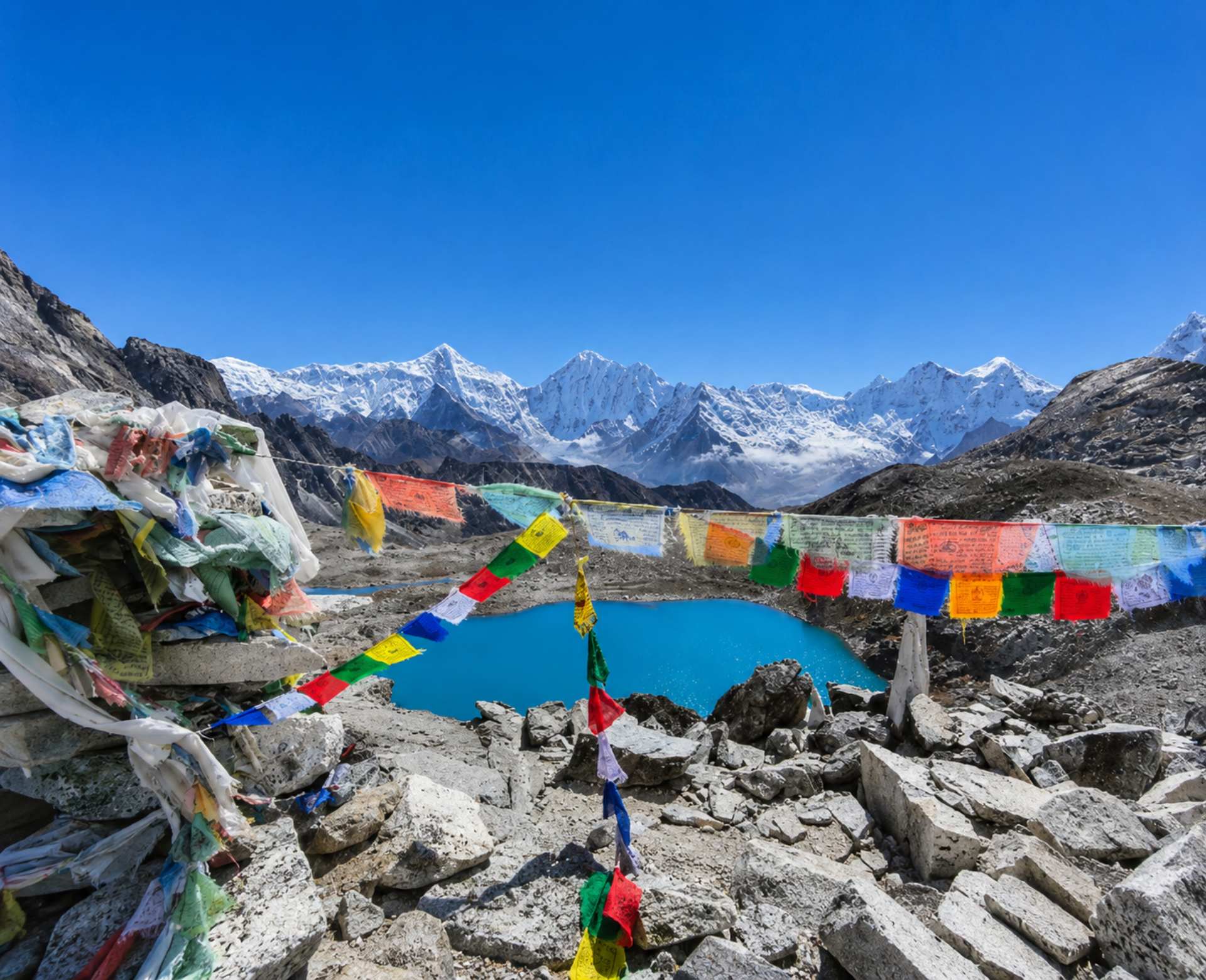 Gokyo Lake surrounded by Himalayan peaks and prayer flags on the Everest Three Passes Trek in Nepal.