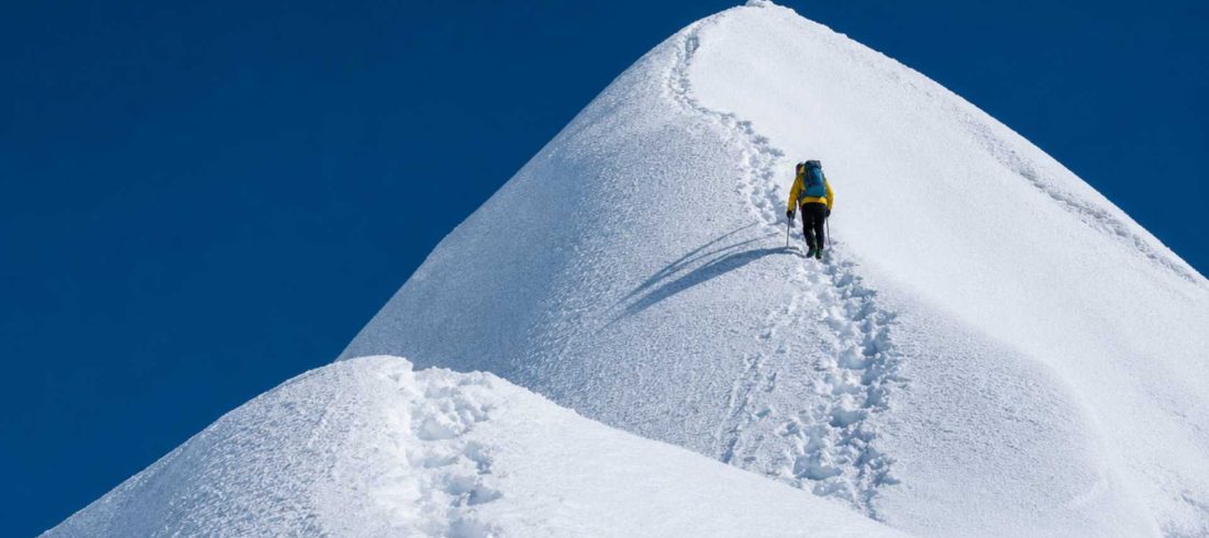 Solo climber ascending a snowy summit ridge during an Island Peak Climbing expedition in Nepal