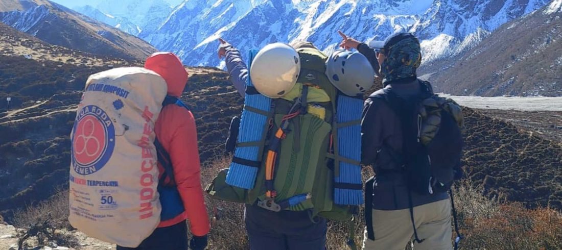 Climbers carrying backpacks, helmets, camping gear, and climbing equipment during a Yala Peak expedition in Langtang, Nepal.