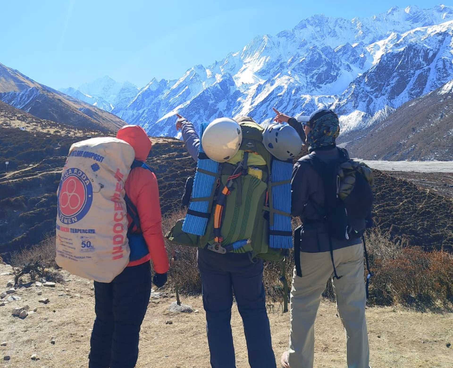 Climbers carrying backpacks, helmets, camping gear, and climbing equipment during a Yala Peak expedition in Langtang, Nepal.