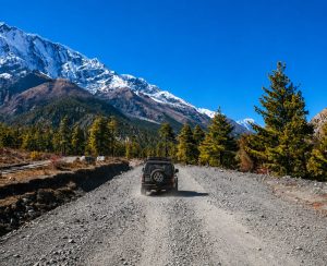 Manang Valley Jeep Tour – Scenic 4WD Adventure in Nepal Manang Valley Jeep Tour on a rugged 4WD road with snow-capped Himalayan mountains in the Annapurna region of Nepal