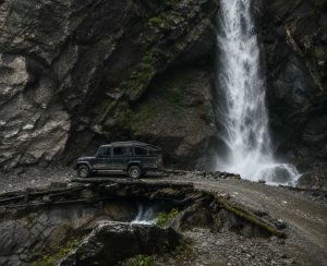 Manang Valley Jeep Tour – Waterfall Crossing by 4WD Jeep Black 4WD jeep crossing a wooden bridge beside a waterfall on the Manang Valley Jeep Tour in Nepal