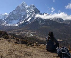 A solo trekker enjoying panoramic mountain views from Nangkartshang in Nepal's Everest region.