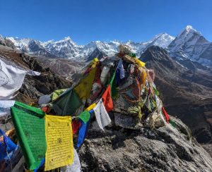 Buddhist prayer flags marking a scenic mountain ridge above Dingboche with sweeping Himalayan views.