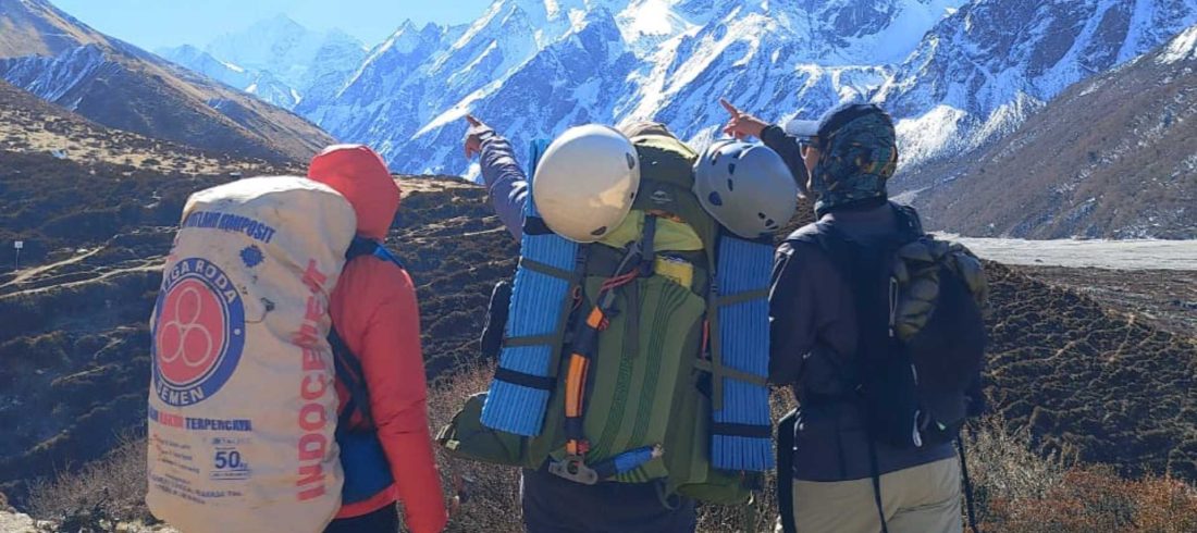 Nepali porters carrying heavy loads on a Himalayan trail with snow peaks behind — things to know before trekking in Nepal