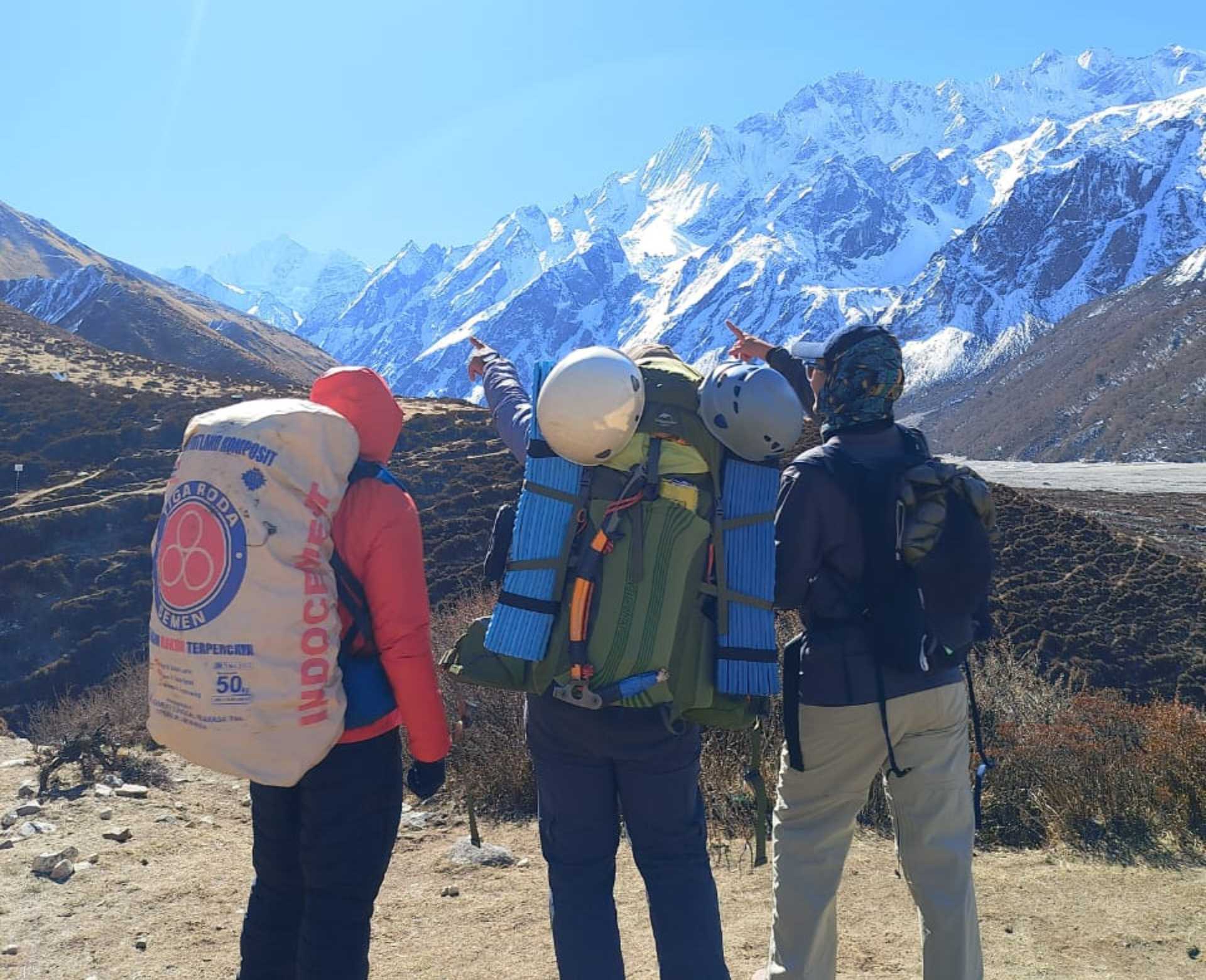 Nepali porters carrying heavy loads on a Himalayan trail with snow peaks behind — things to know before trekking in Nepal