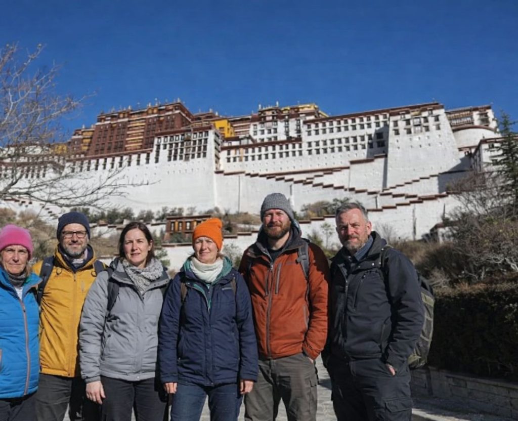Group of trekkers standing in front of the Potala Palace during the Tibet Overland Tour from Nepal